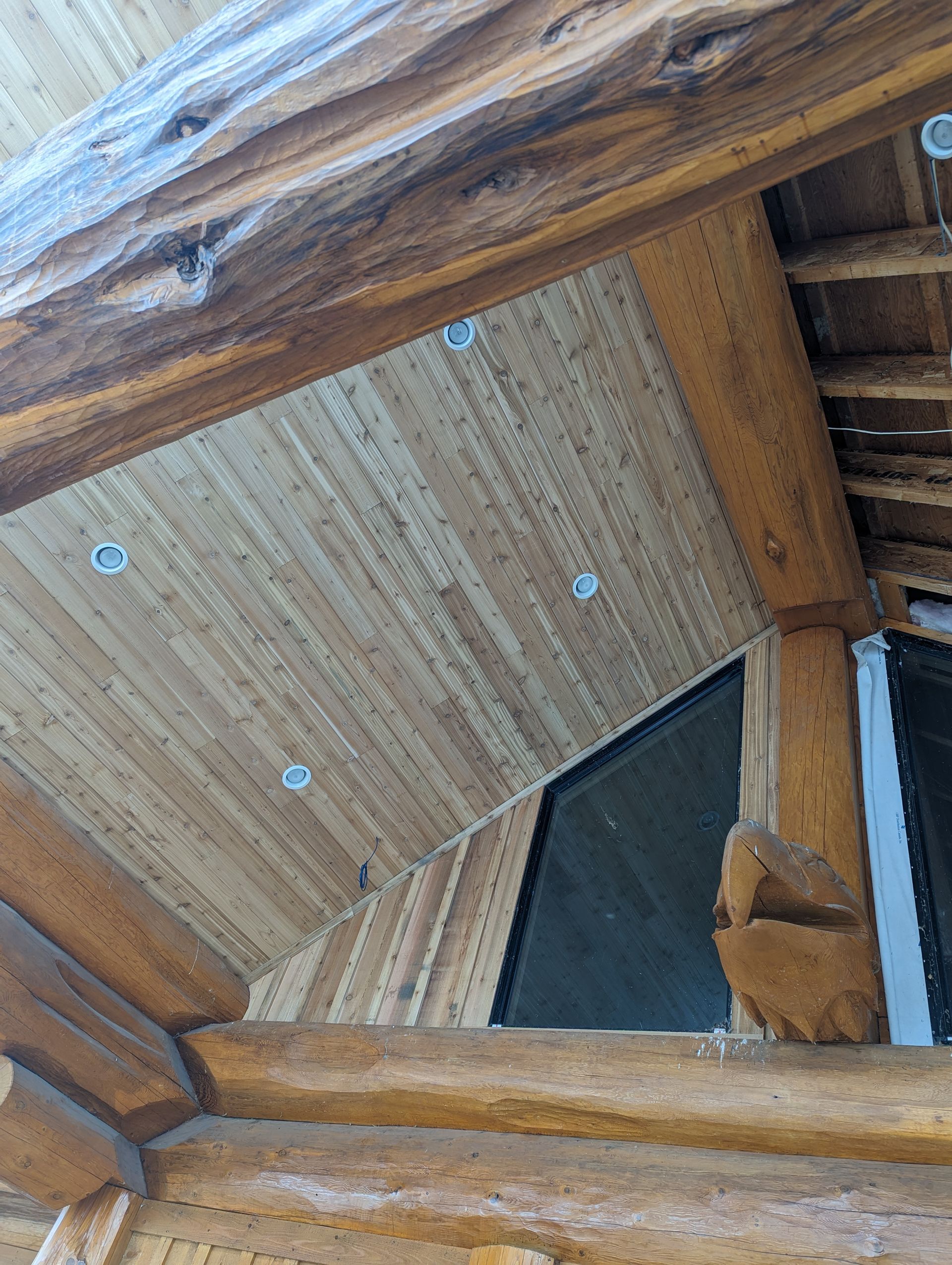 Wooden ceiling with recessed lights, supported by large timber beams.