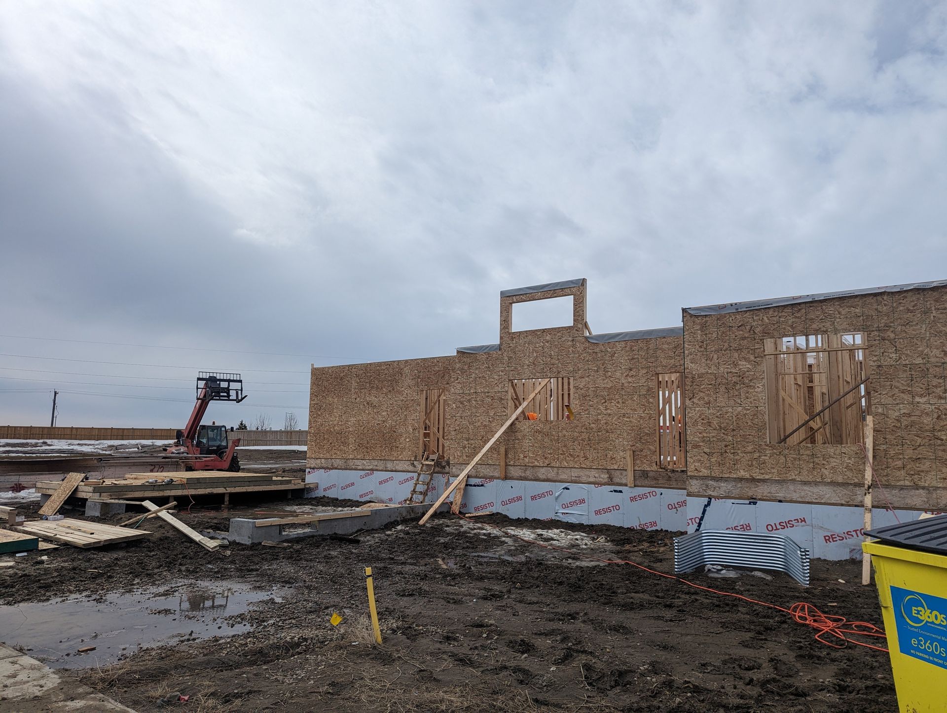 A large building is being built in a muddy field.