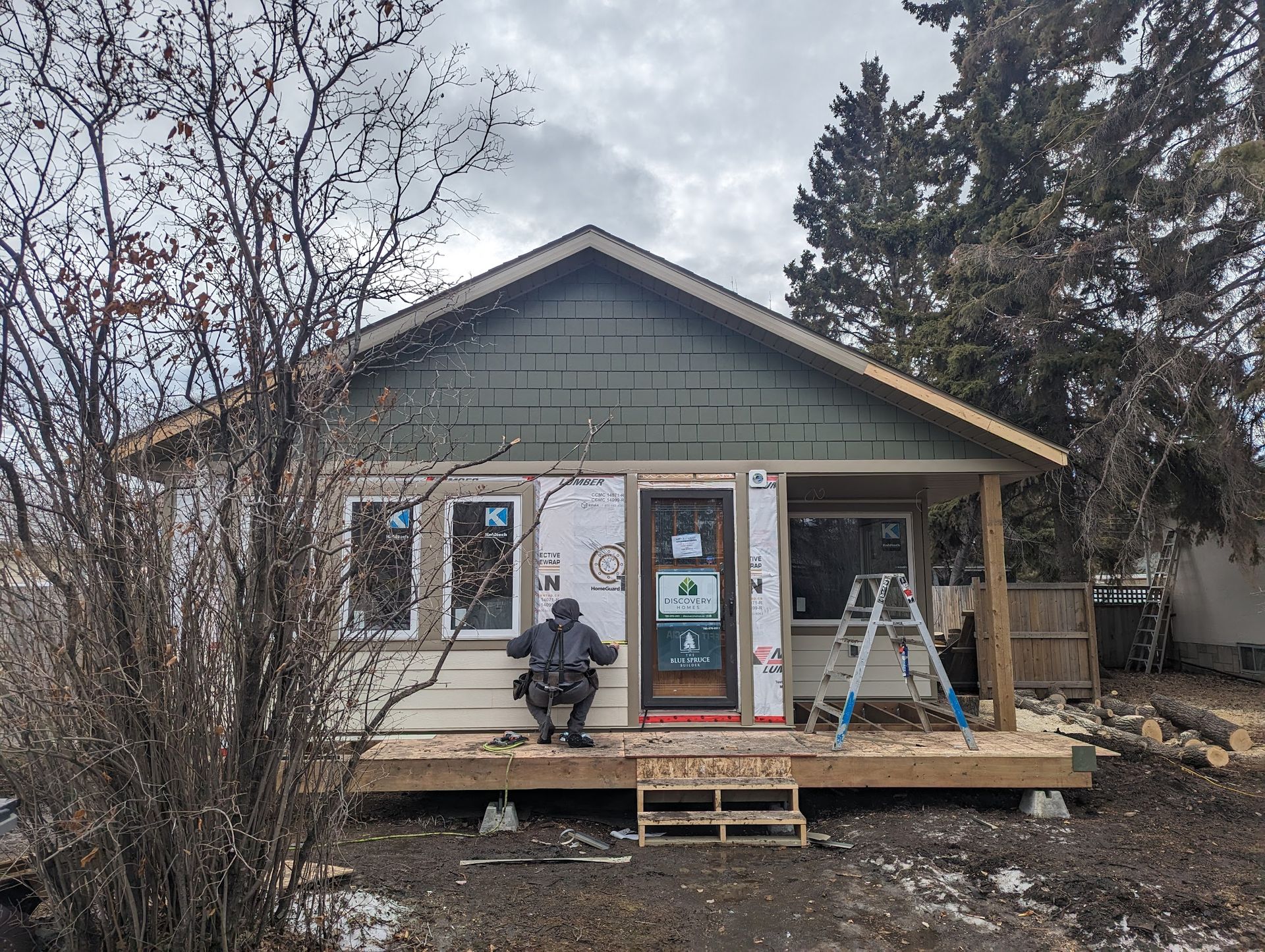 A man is sitting on the porch of a house under construction.