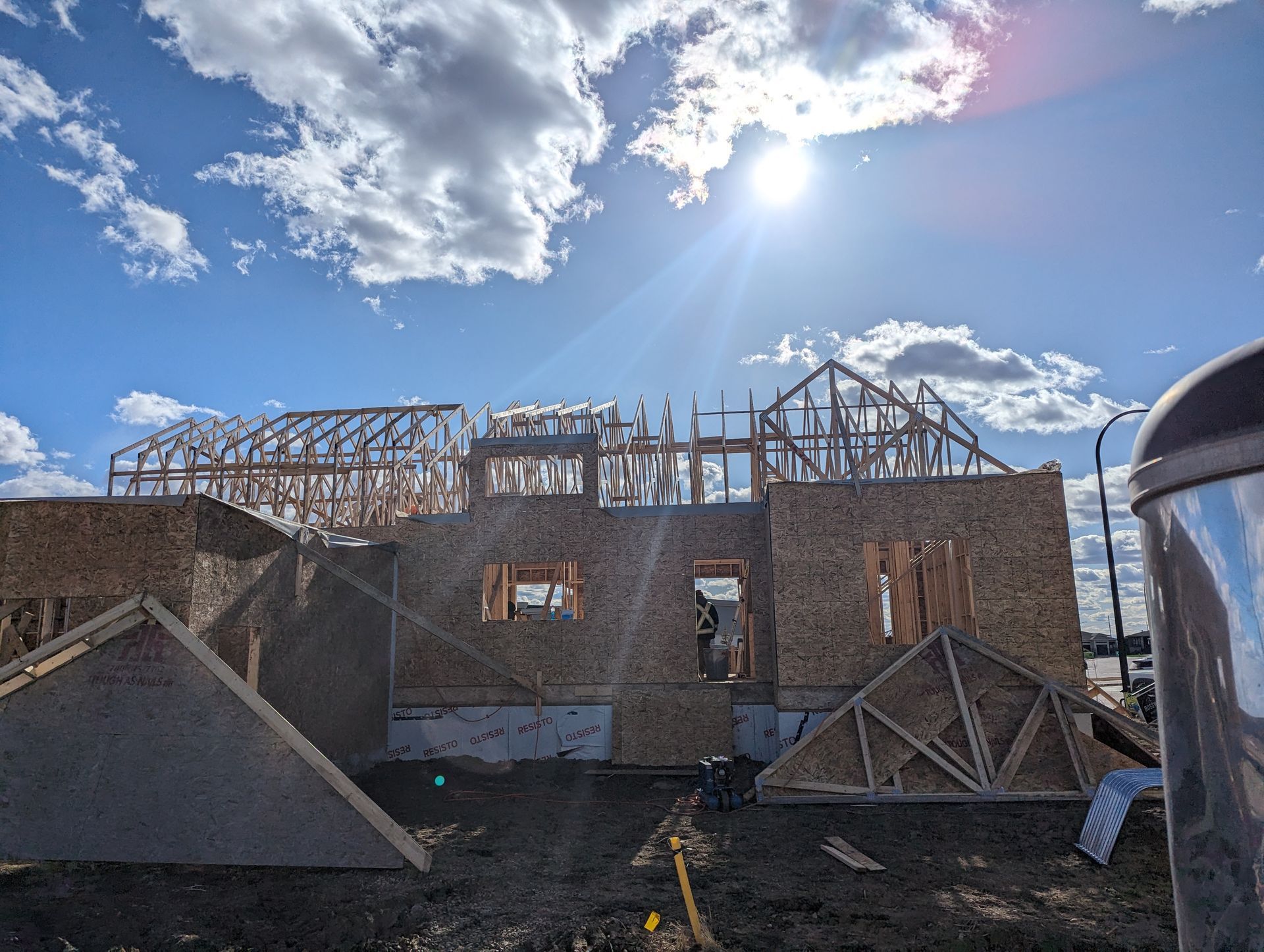 A house is being built on a sunny day with the sun shining through the clouds.