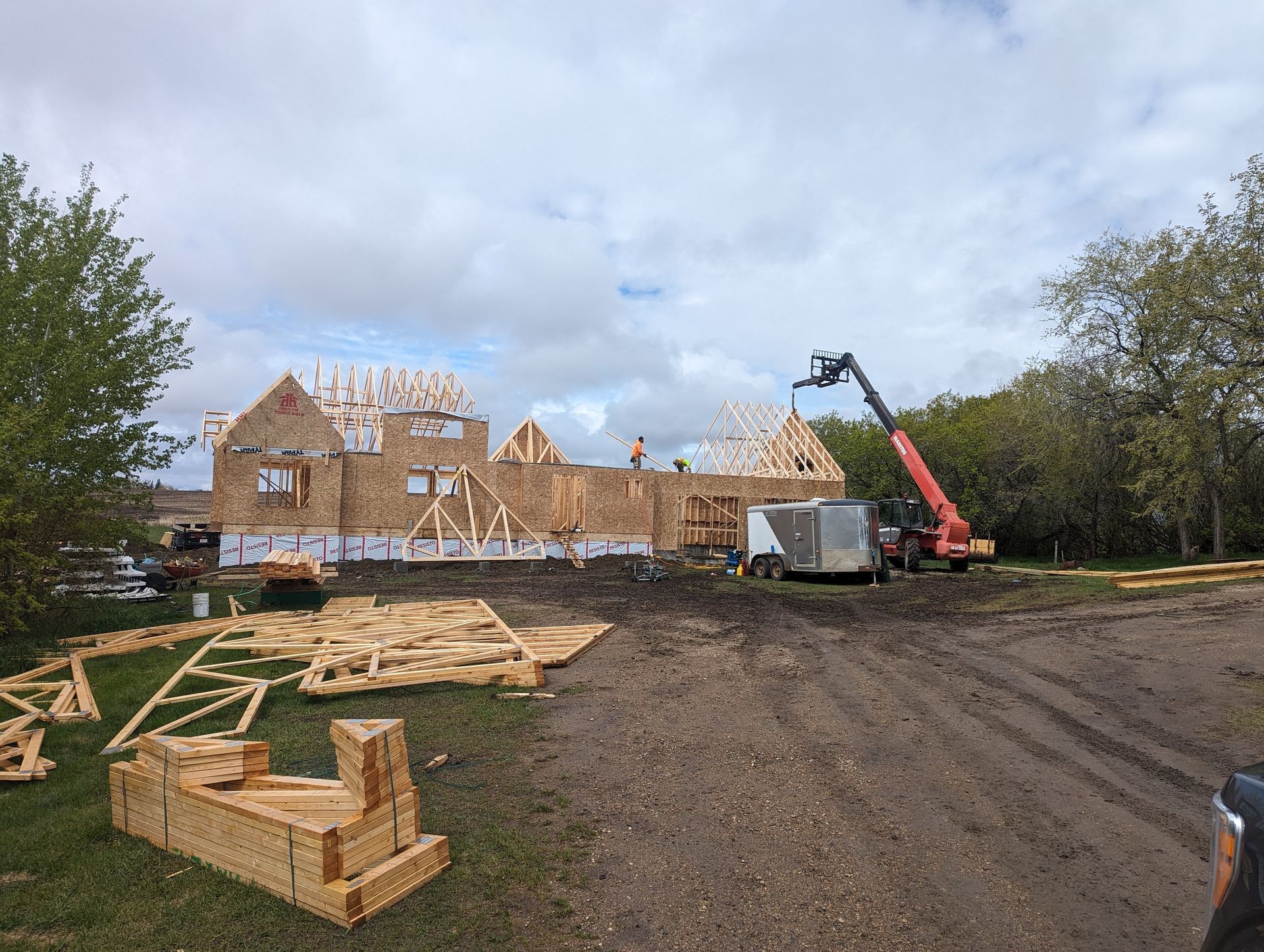 A large house is being built in the middle of a dirt field.