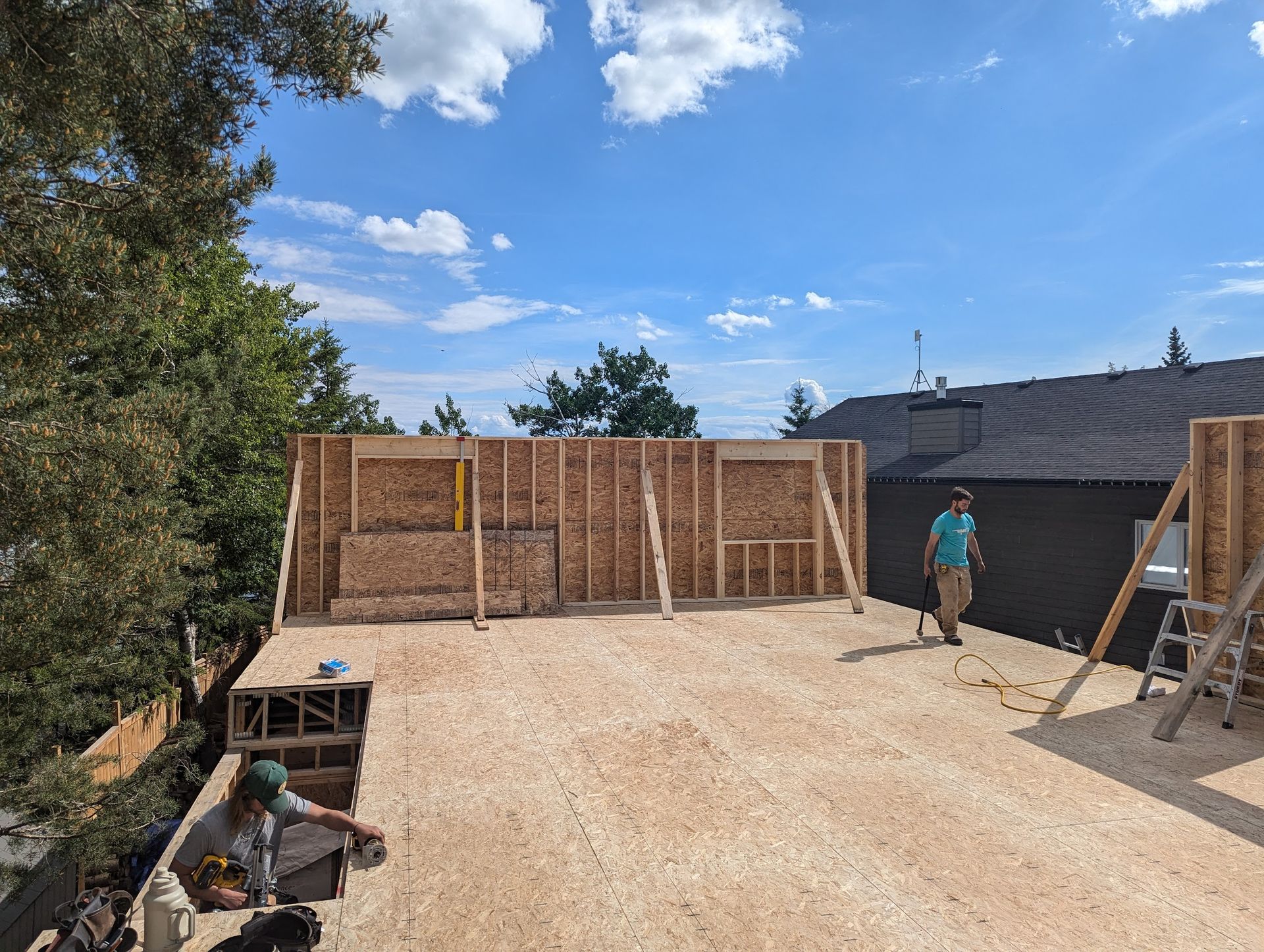 A man is standing on the roof of a house under construction.