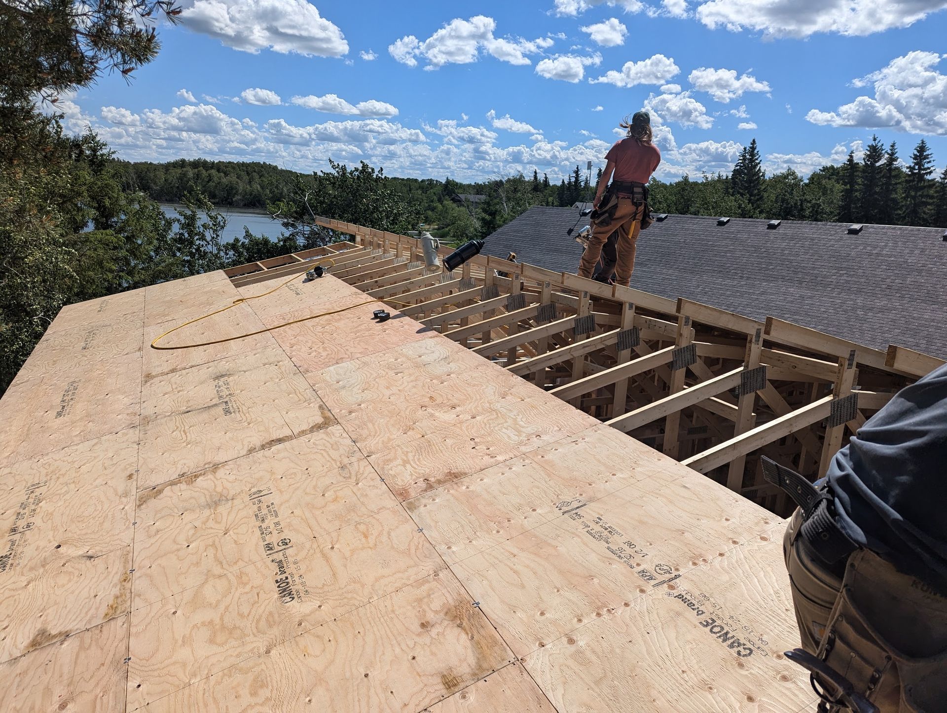 A man is standing on top of a wooden roof.