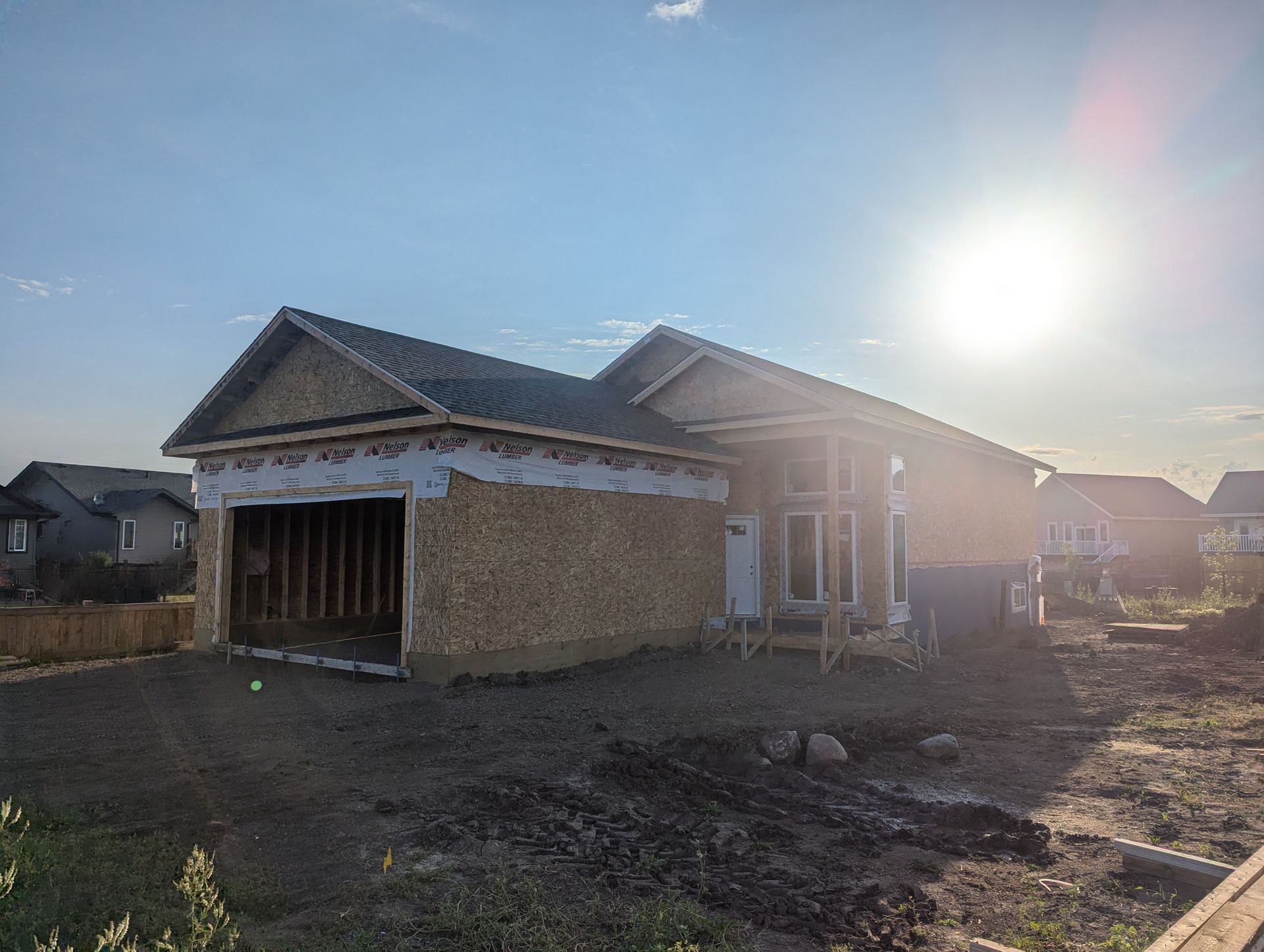 A house is being built in a residential area with the sun shining through the windows.
