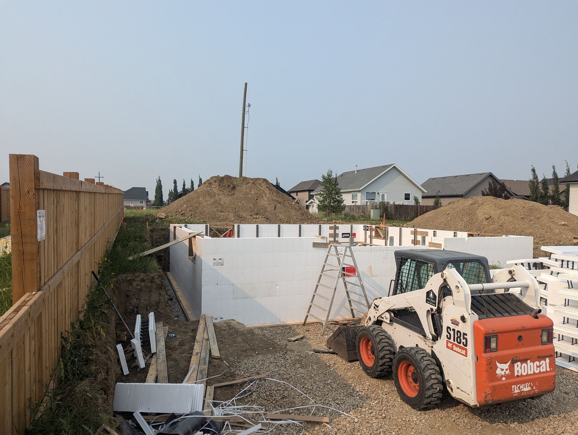 A bobcat is parked in front of a building under construction.