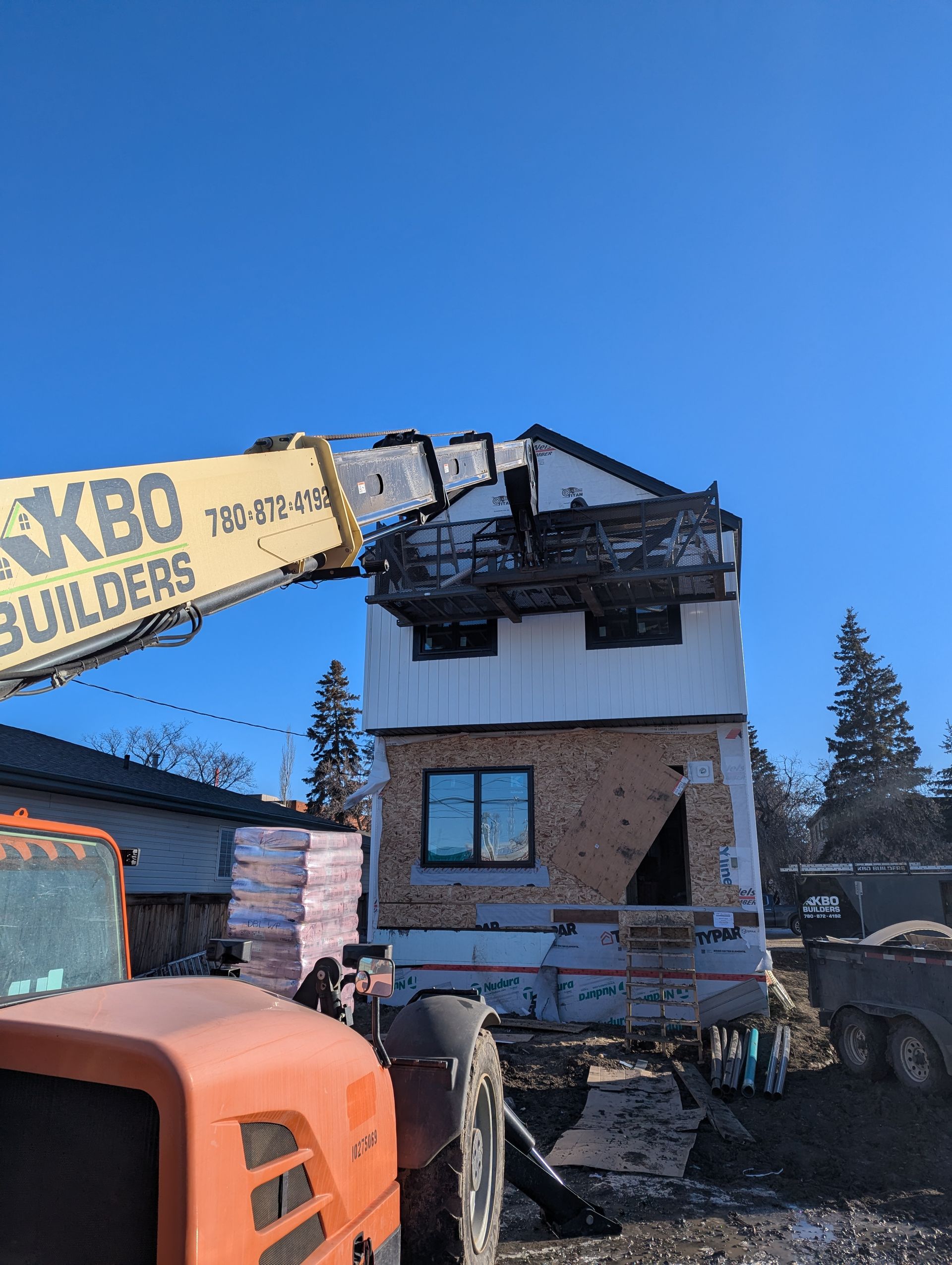 Construction site: a partially deconstructed building with a crane arm holding a work platform.