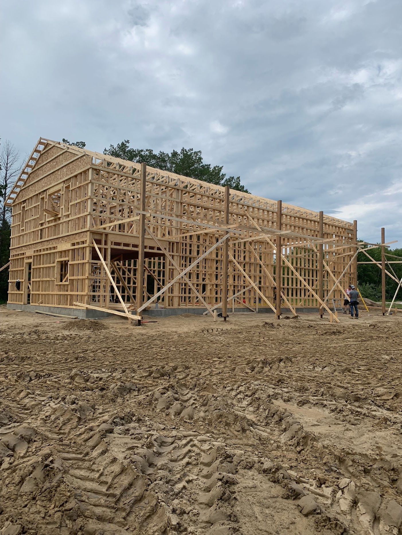 A large wooden building is being built in a dirt field.