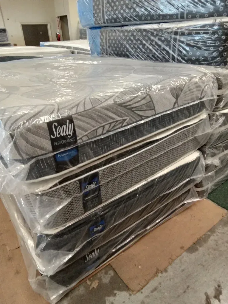 Stacked Sealy mattresses wrapped in plastic on a warehouse pallet