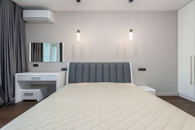 Modern bedroom with a bed, vanity, wall lights, air conditioner, and curtains