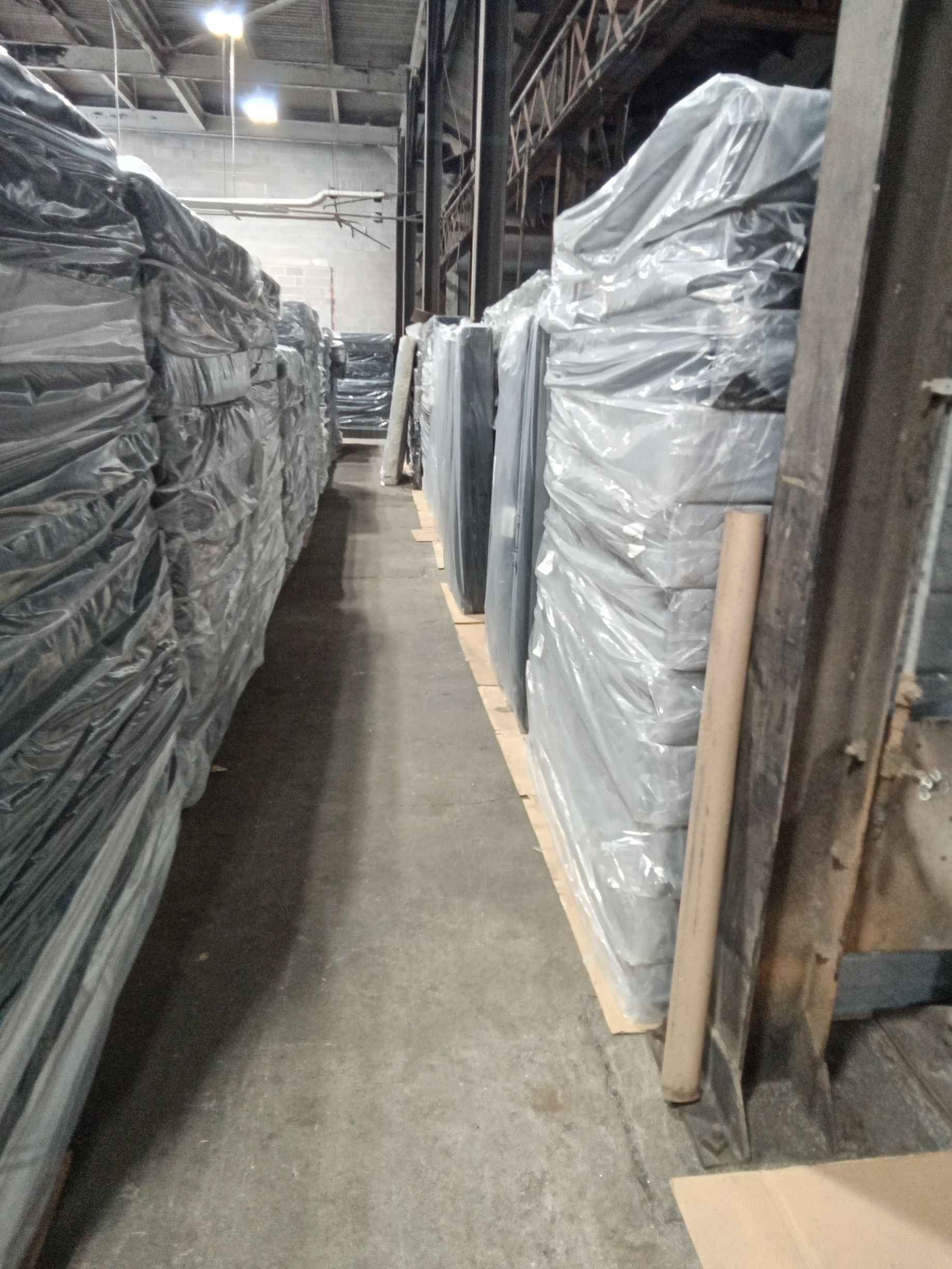 Narrow warehouse aisle lined with wrapped pallets and stacked goods on both sides