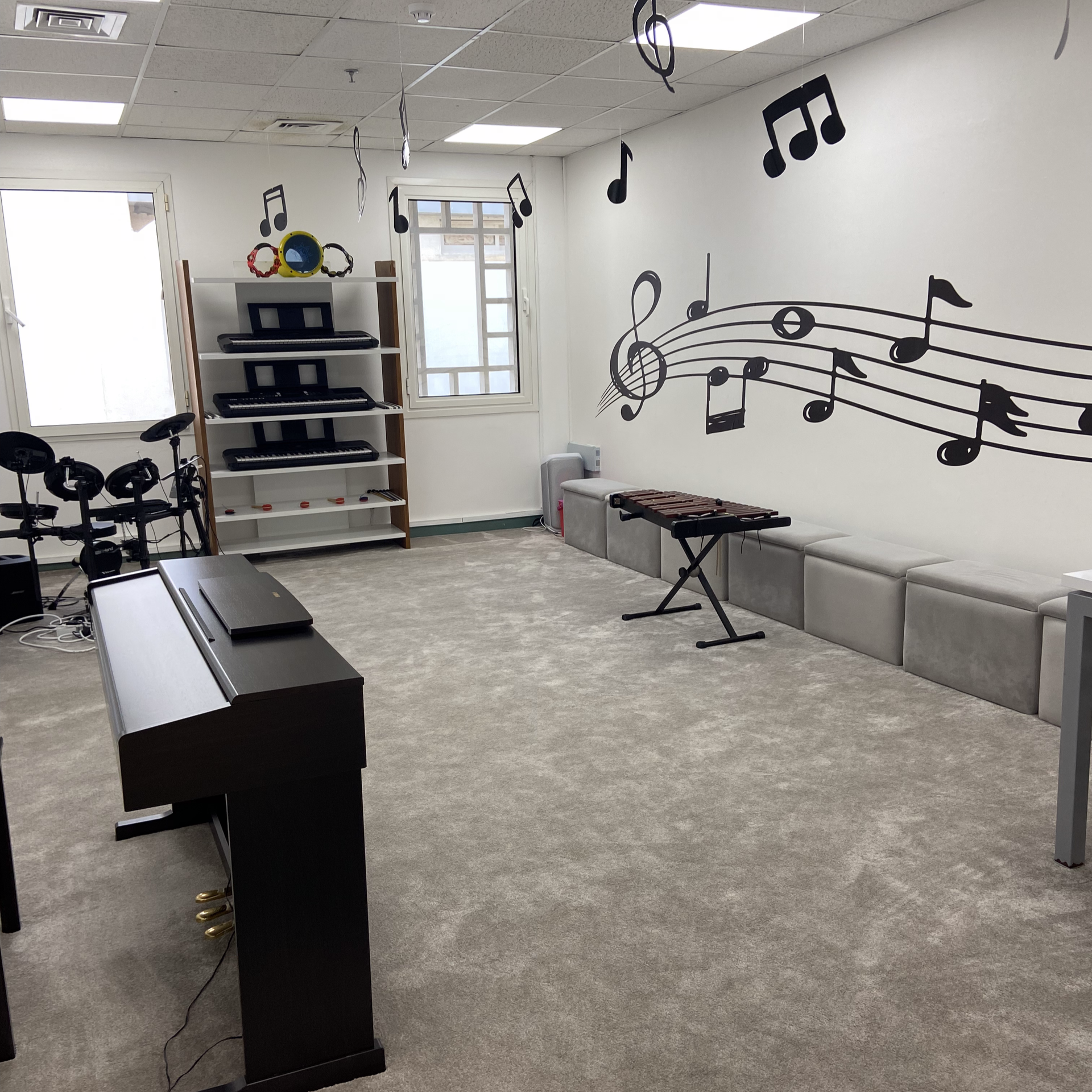 Music classroom with pianos, keyboards, and decorative music notes on the walls.