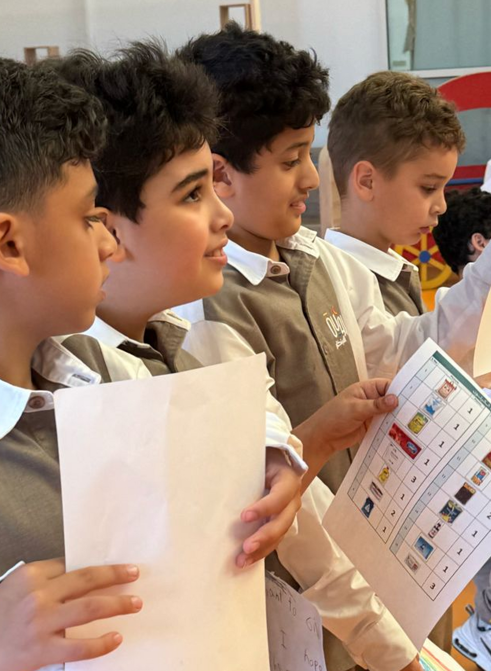 A group of young boys are holding papers in their hands.