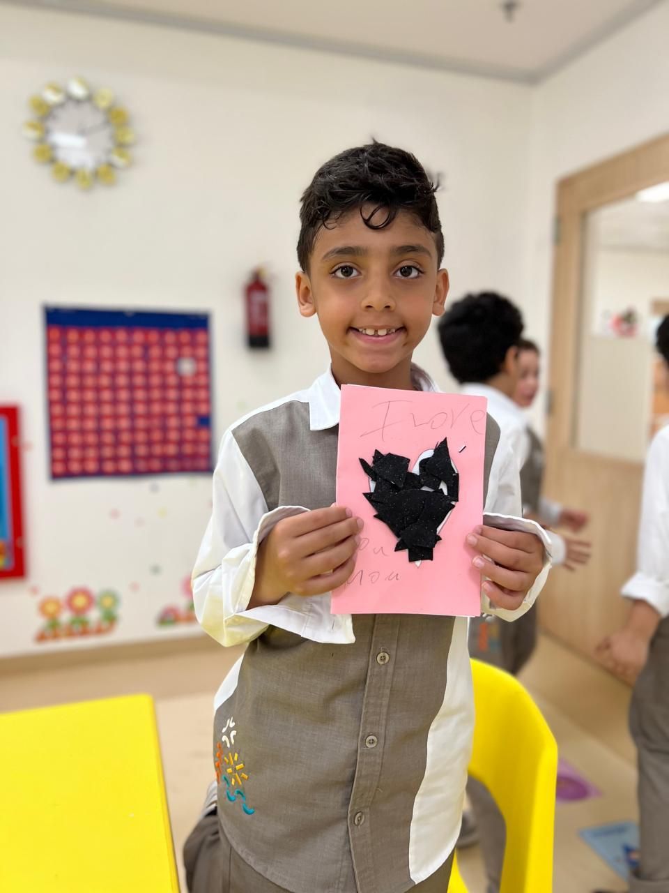 A young boy is holding a piece of paper with a black cat on it