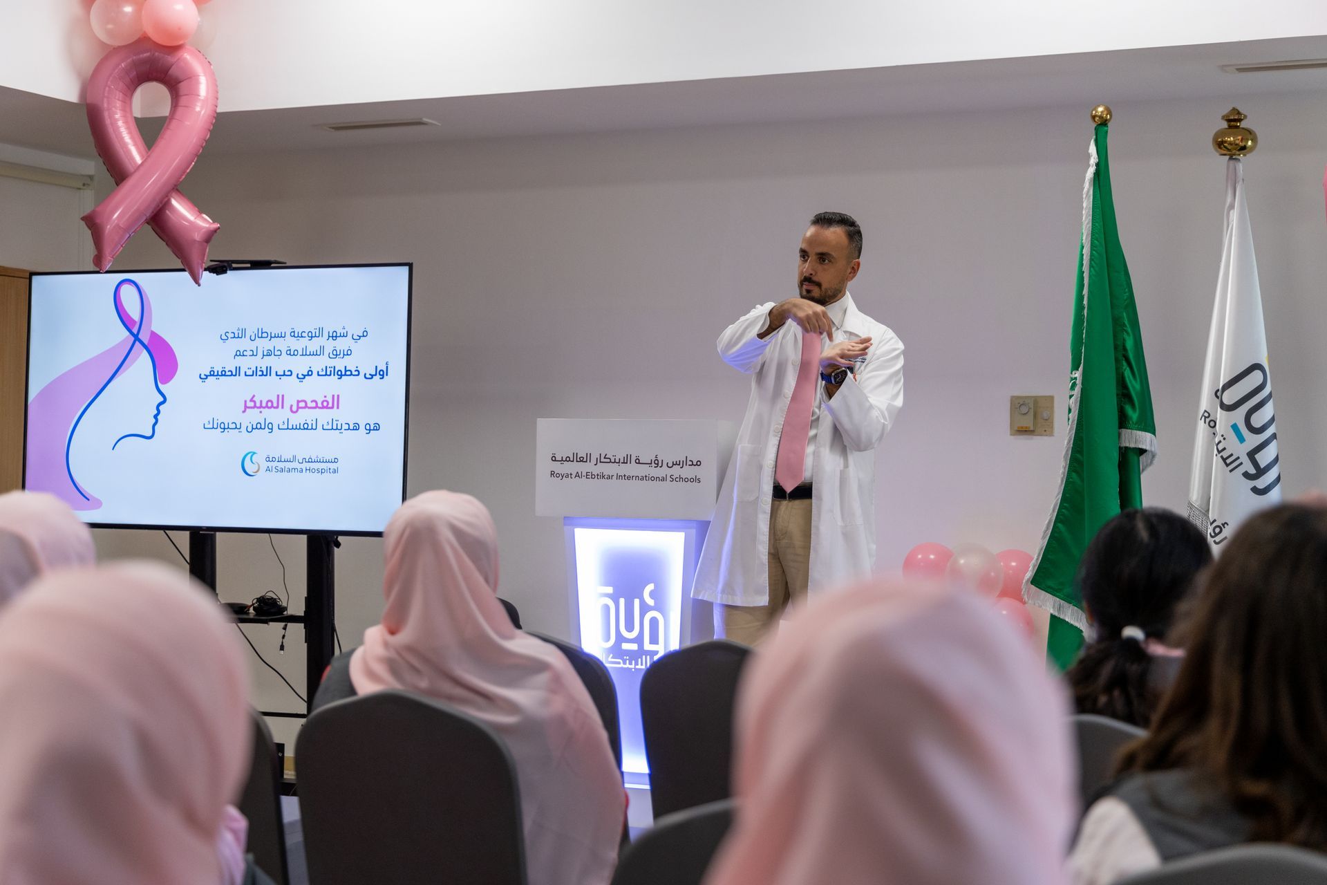 A man in a pink shirt is giving a presentation to a group of women.