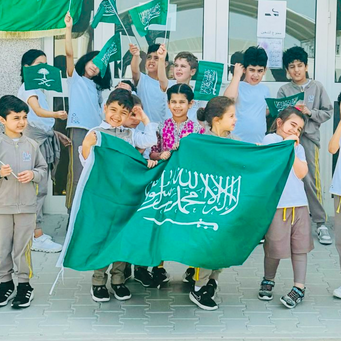 A group of children holding a green flag with arabic writing on it