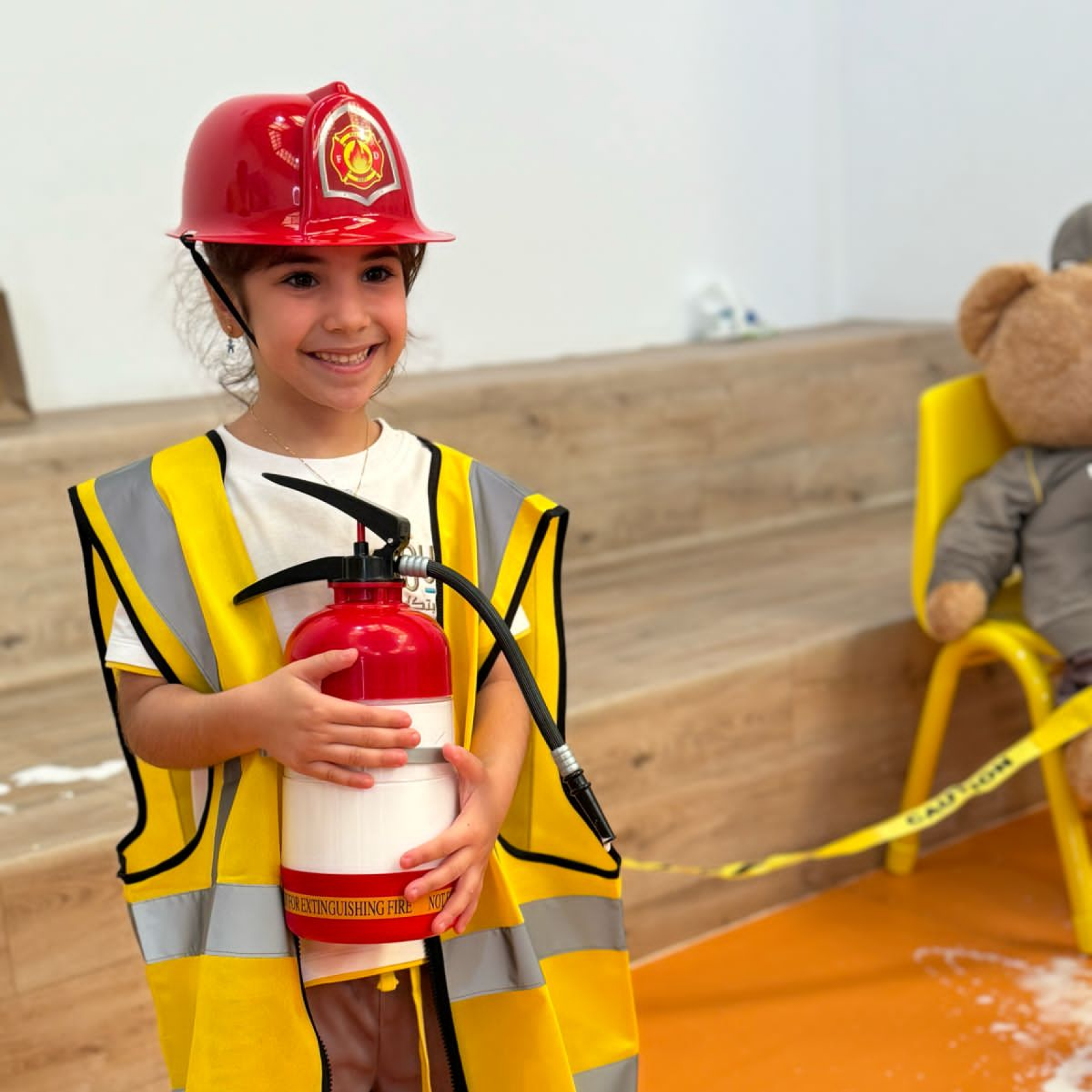 A little girl dressed as a fireman holding a fire extinguisher