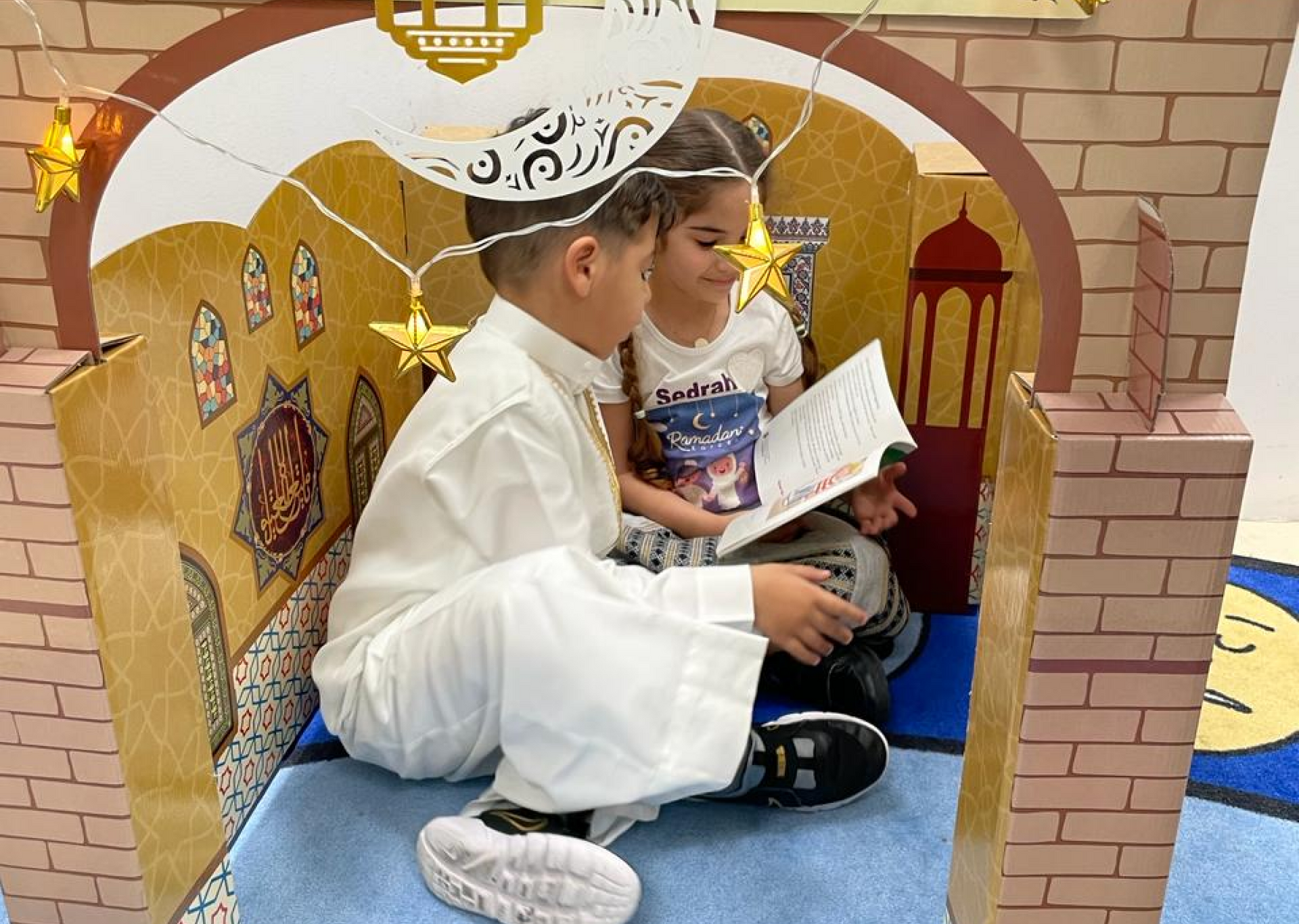 A boy and a girl are sitting in a castle reading a book.