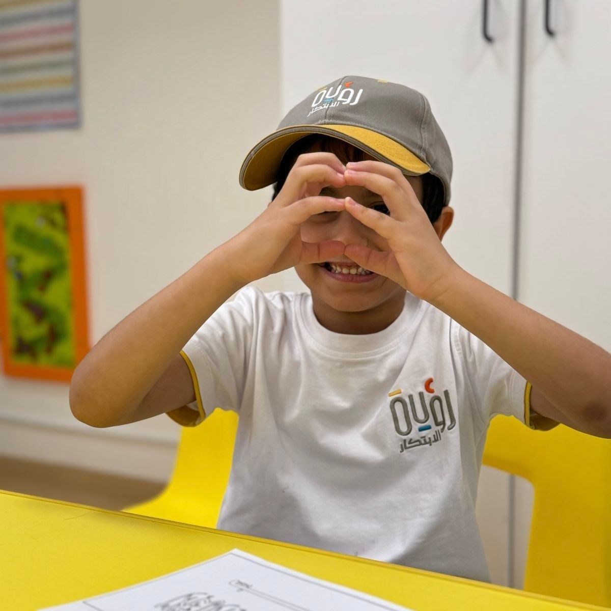 A young boy wearing a hat and a white t-shirt with the word oui on it