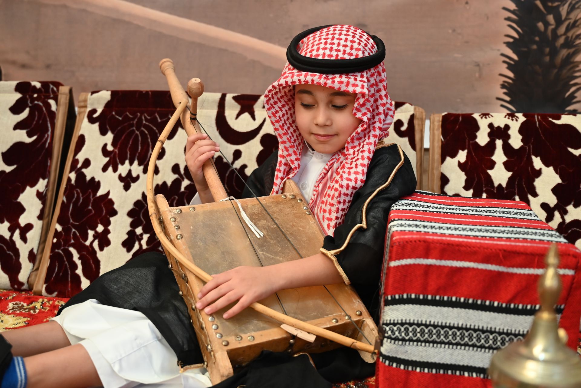 A young boy is sitting on a couch playing a wooden instrument.