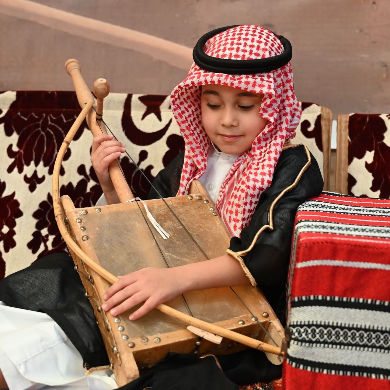A young boy in a traditional costume is playing a musical instrument