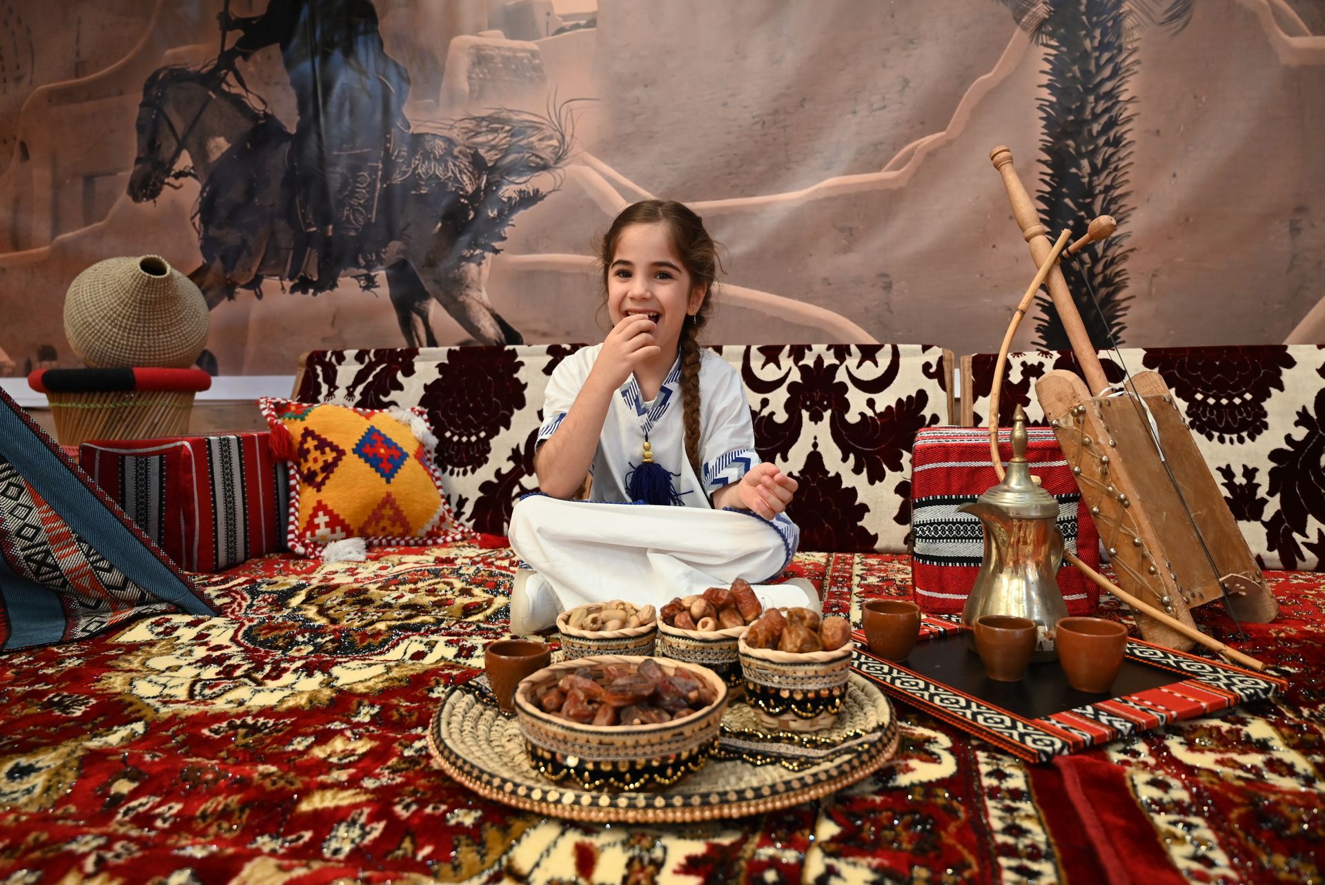 A little girl is sitting on a couch eating nuts.