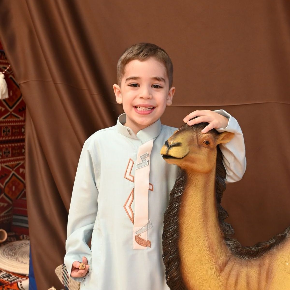 A young boy standing next to a statue of a camel