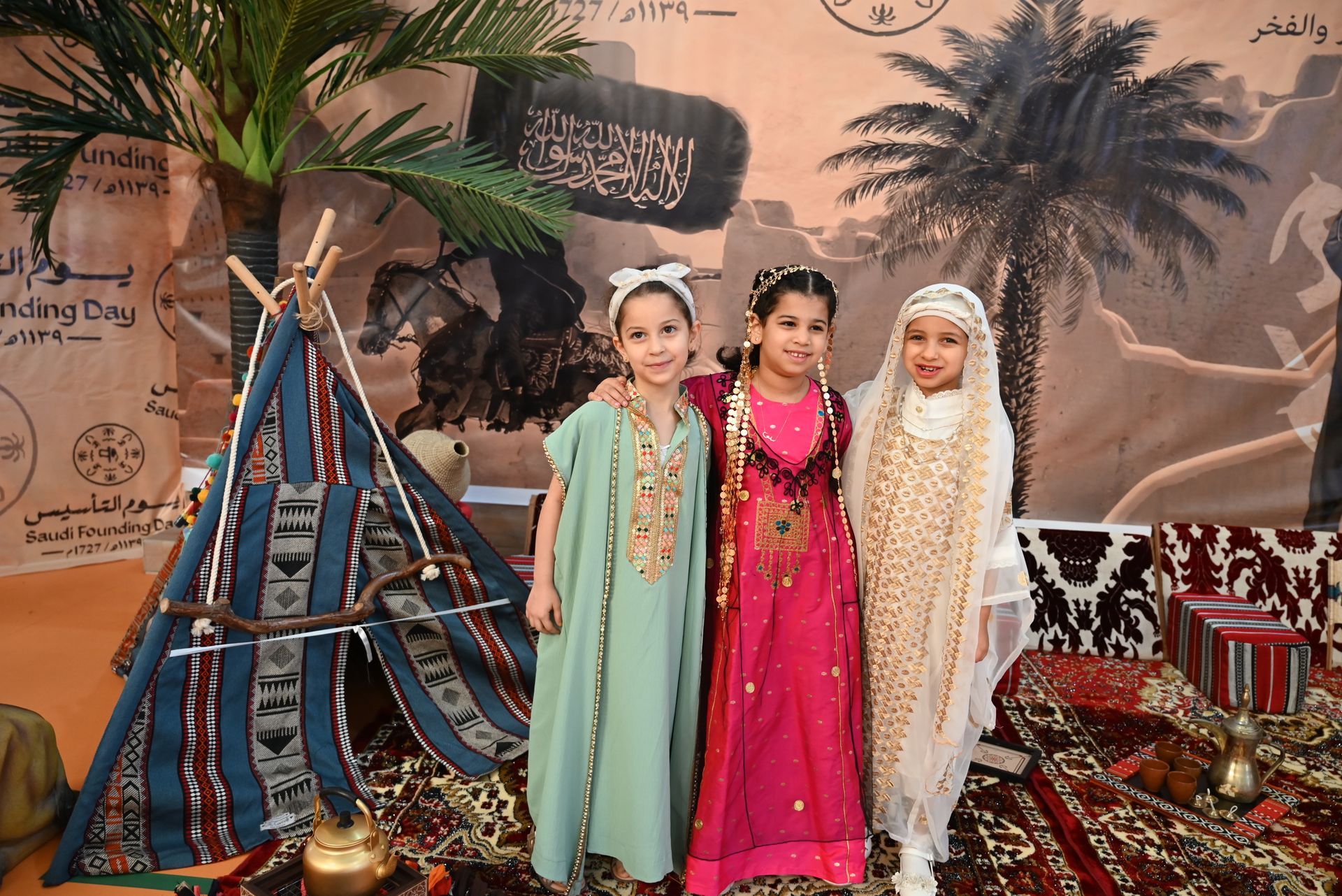 Three little girls in traditional arabic costumes are posing for a picture.