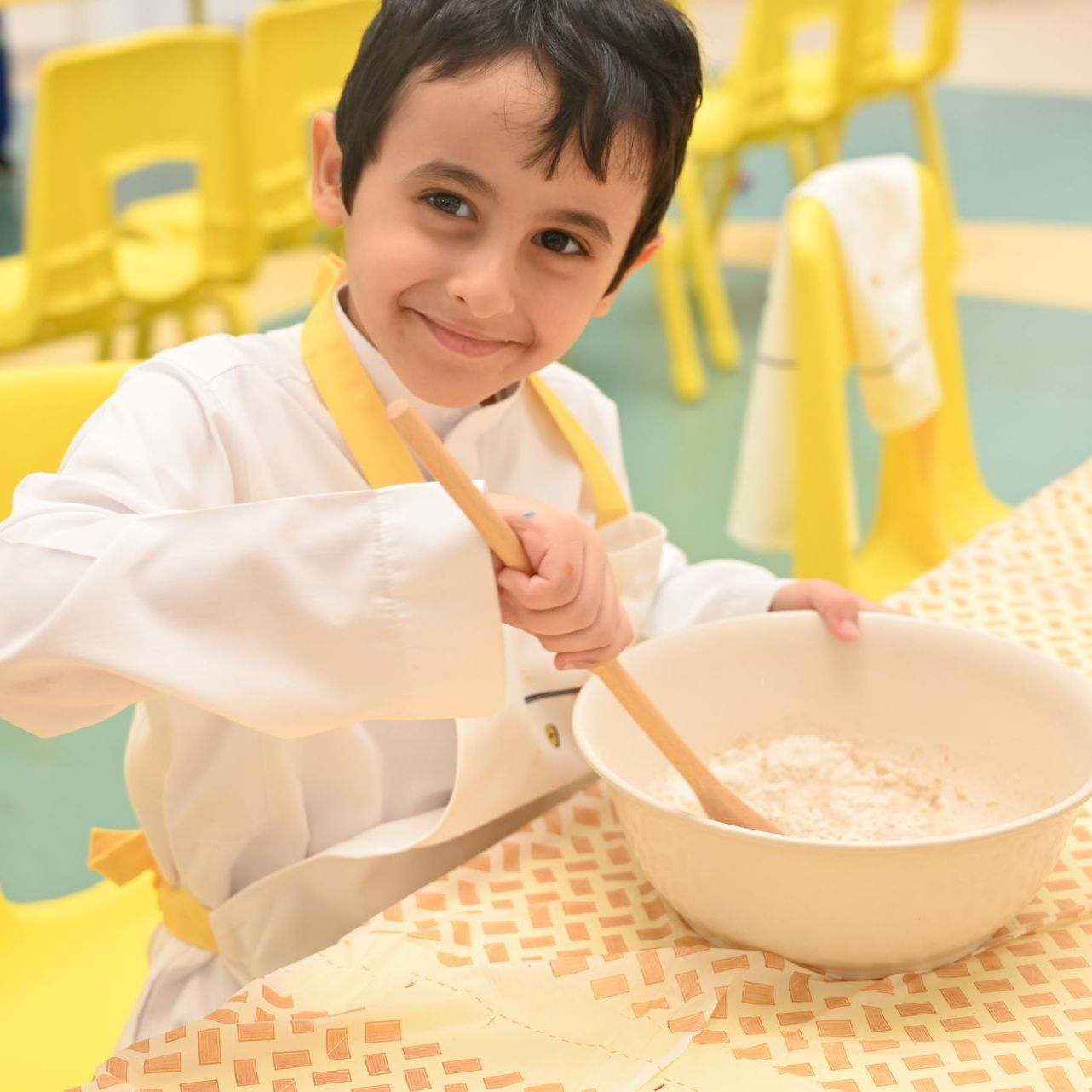A young boy is holding a wooden spoon over a bowl of food