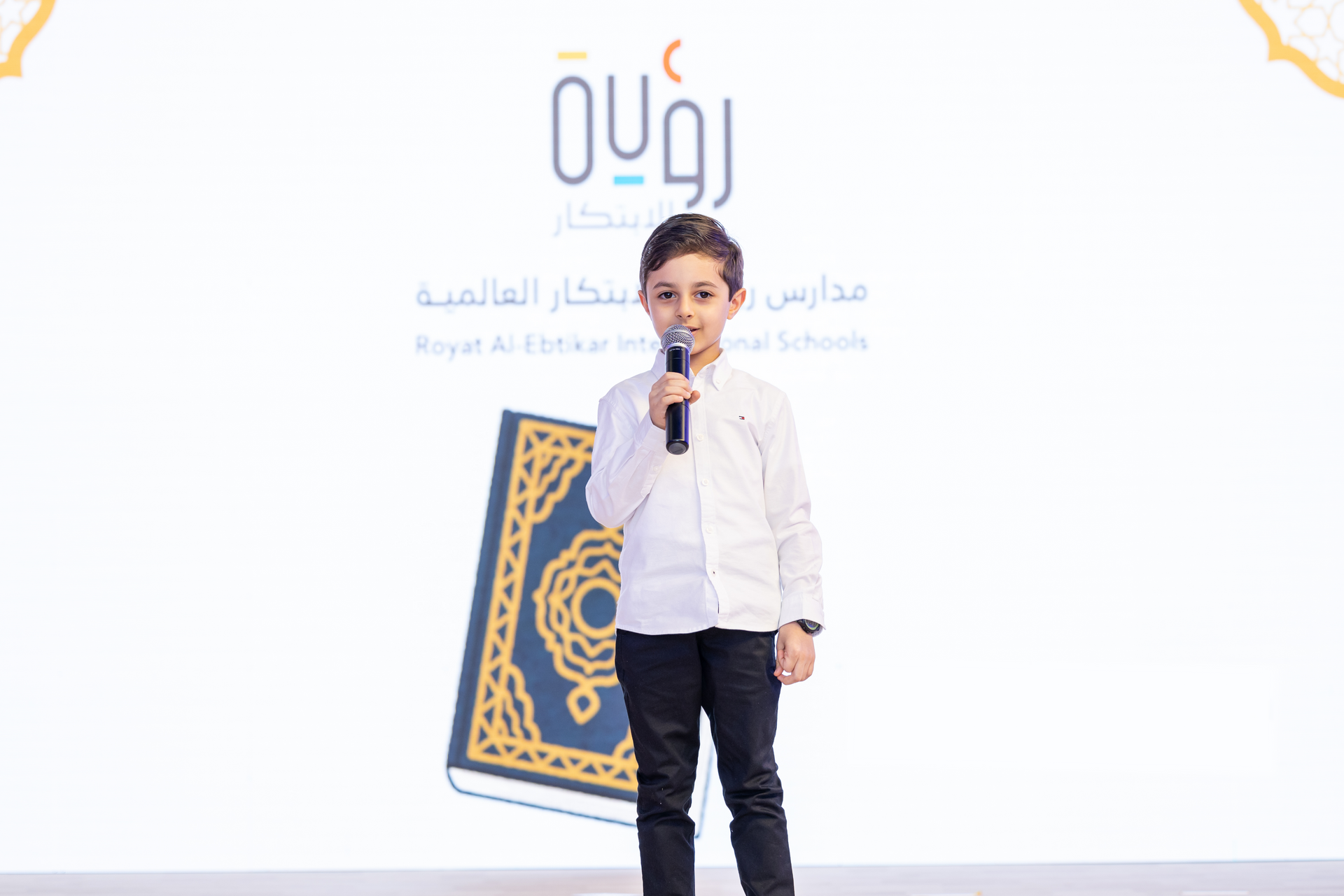 A young boy is holding a microphone in front of a book.