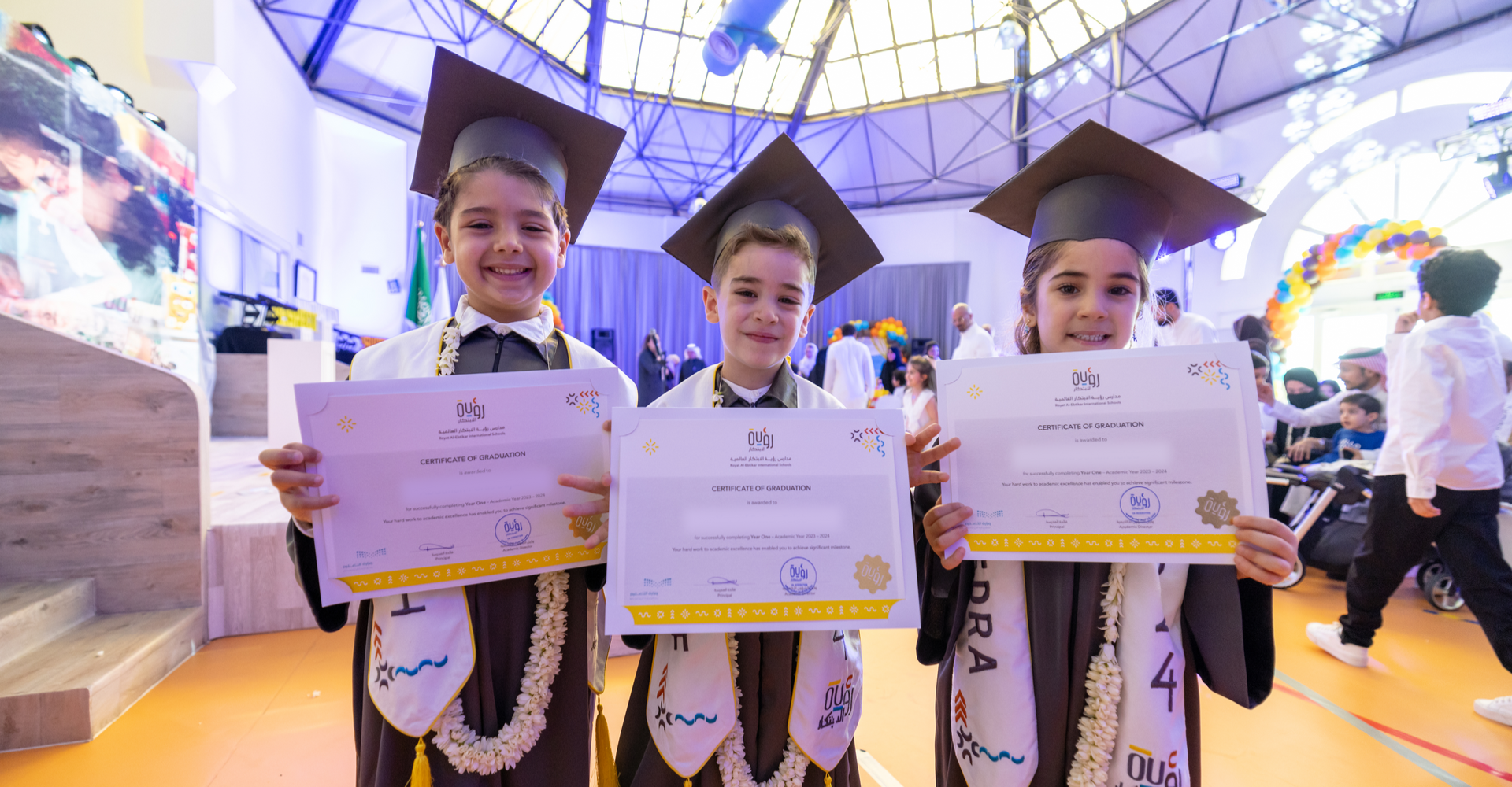 Three students in graduation caps and gowns are holding their diplomas.