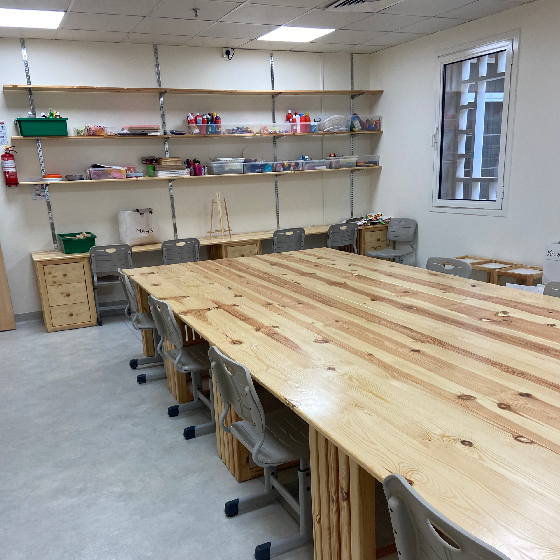 A group of young boys are sitting at a table drawing on papers