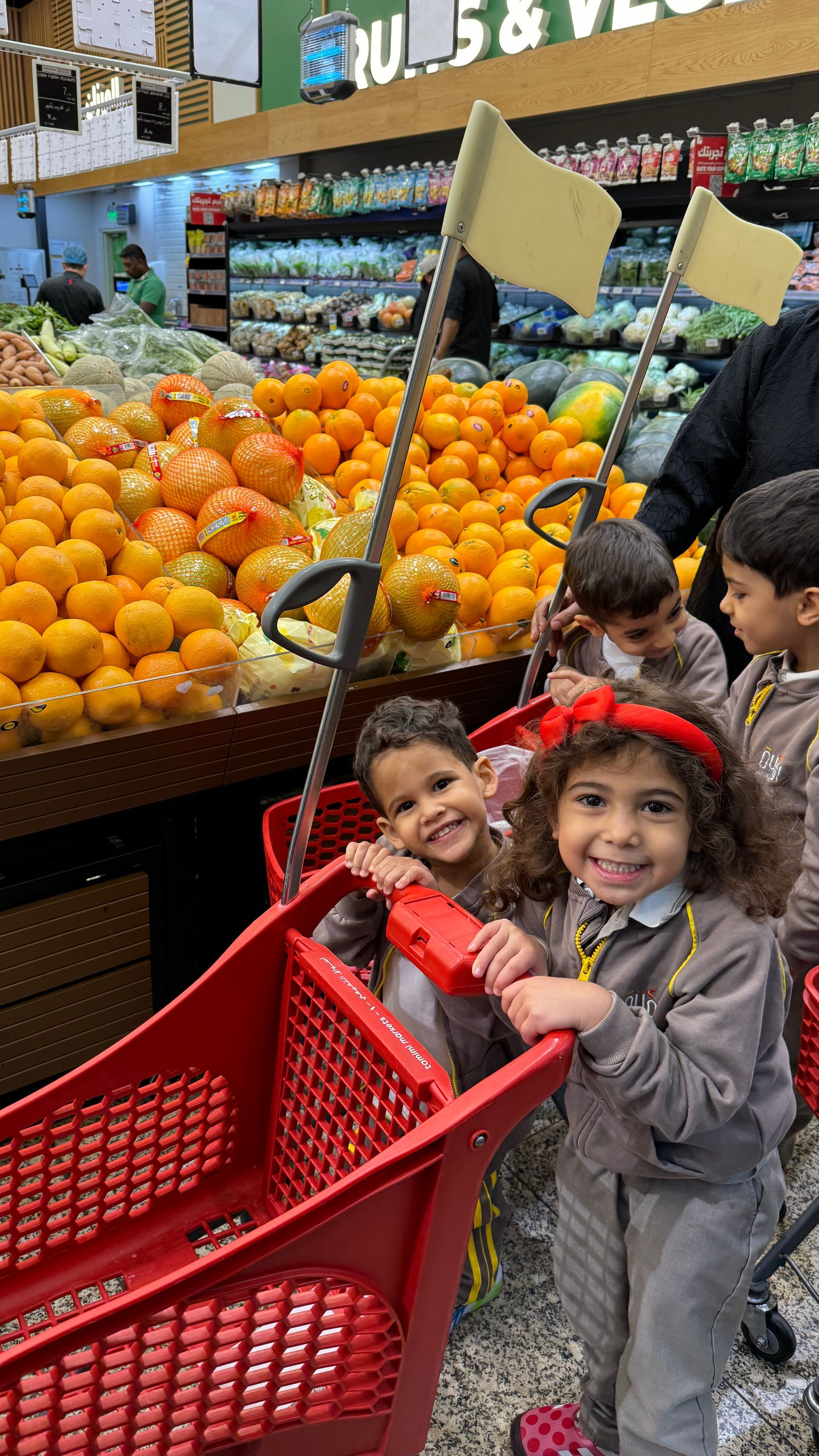 A group of children are pushing a shopping cart in a grocery store.