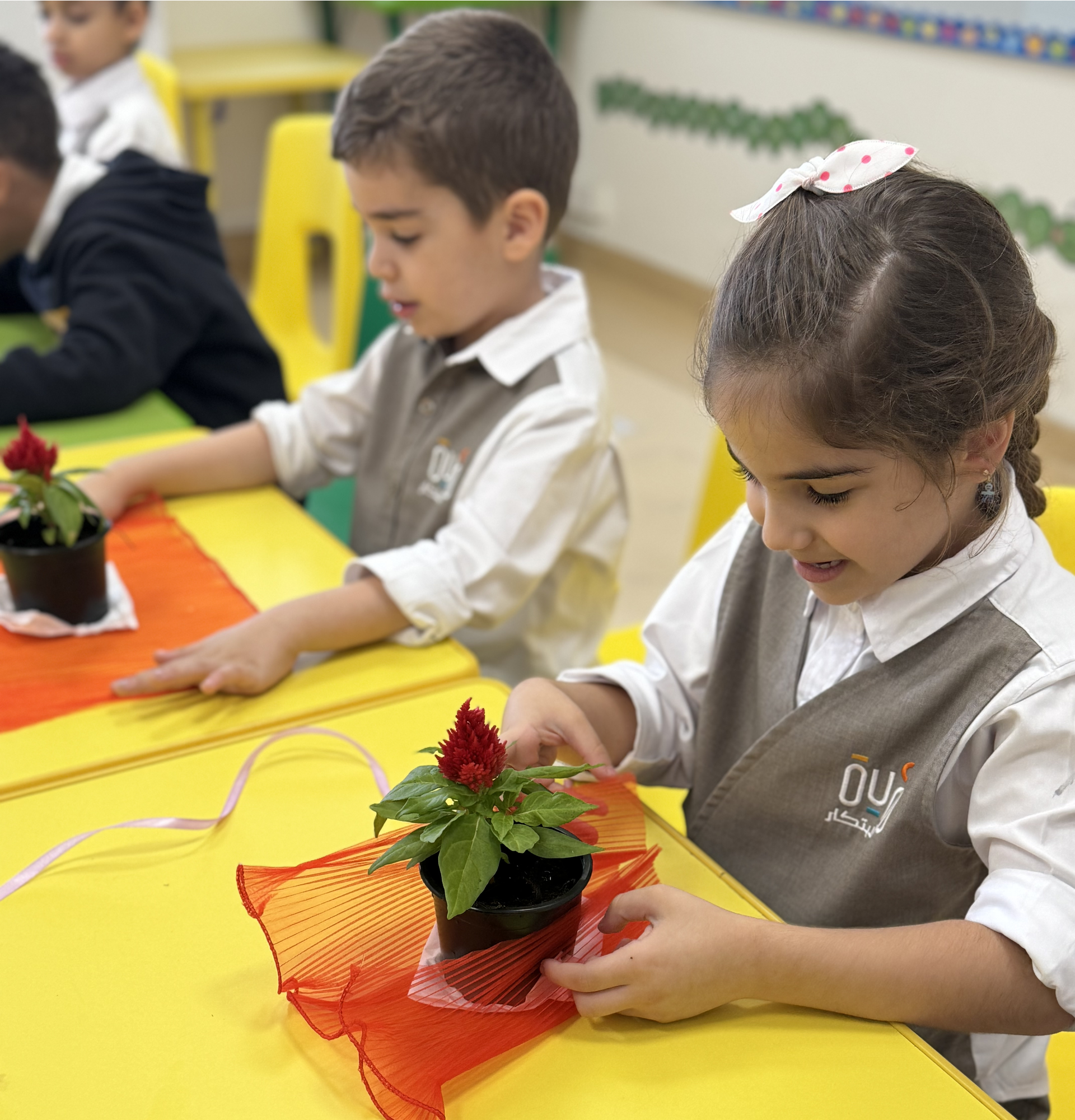 A boy and a girl are sitting at a table playing with potted plants