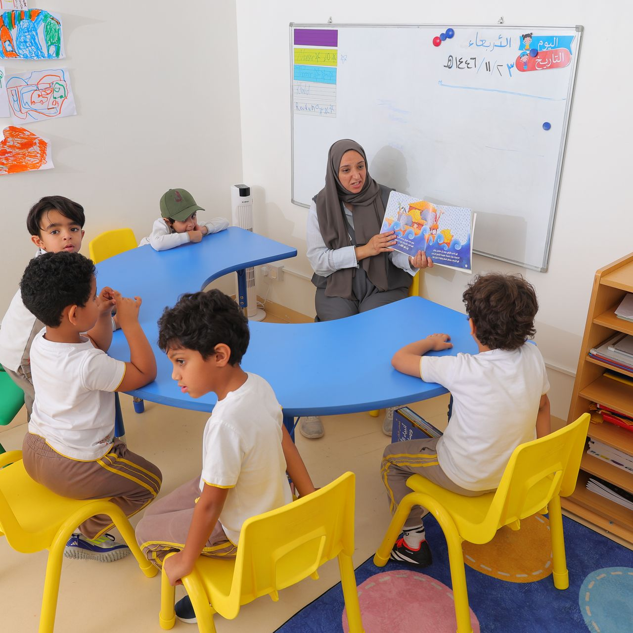 مجموعة من الأولاد الصغار يجلسون على طاولة يرسمون