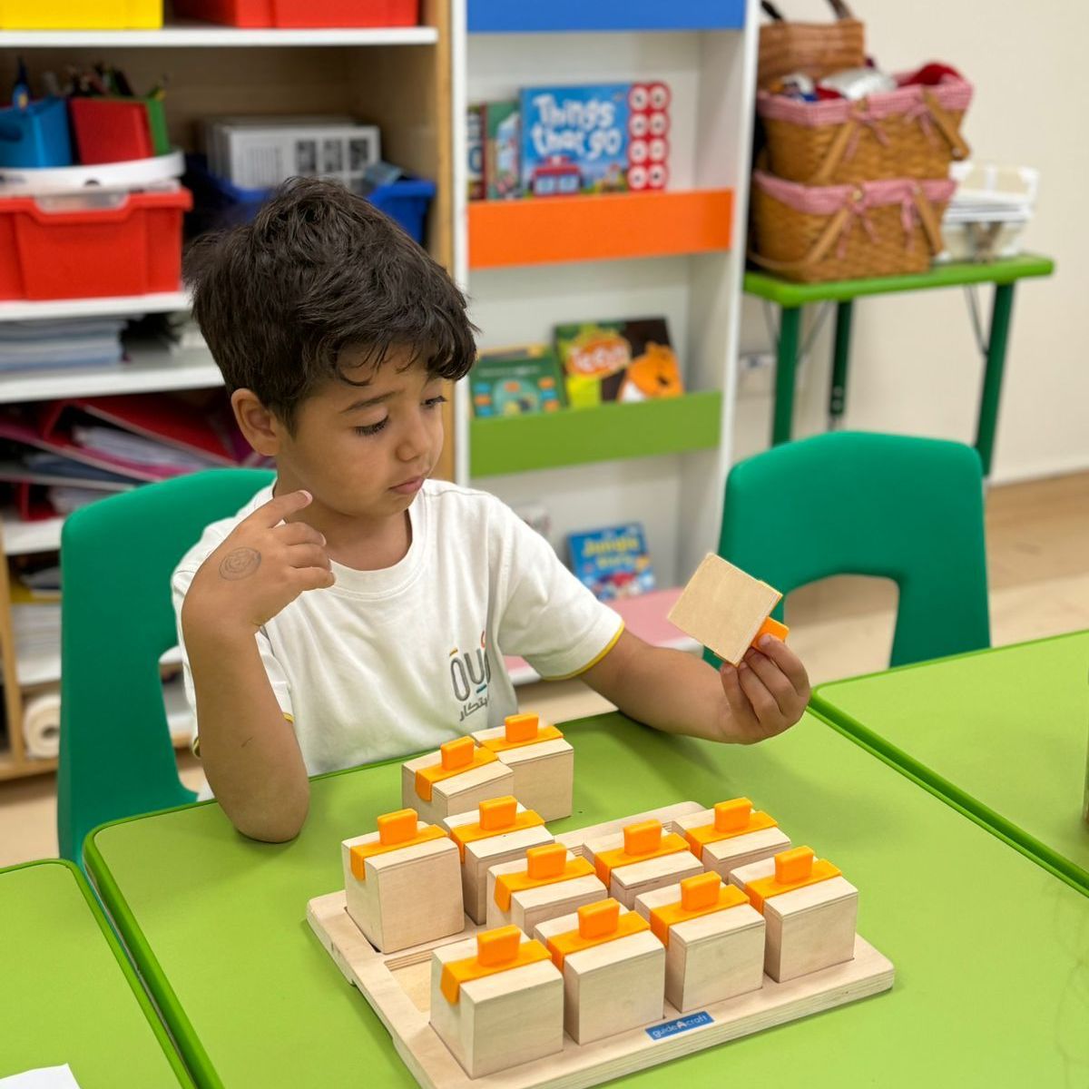 A young boy is sitting at a table playing with wooden blocks.