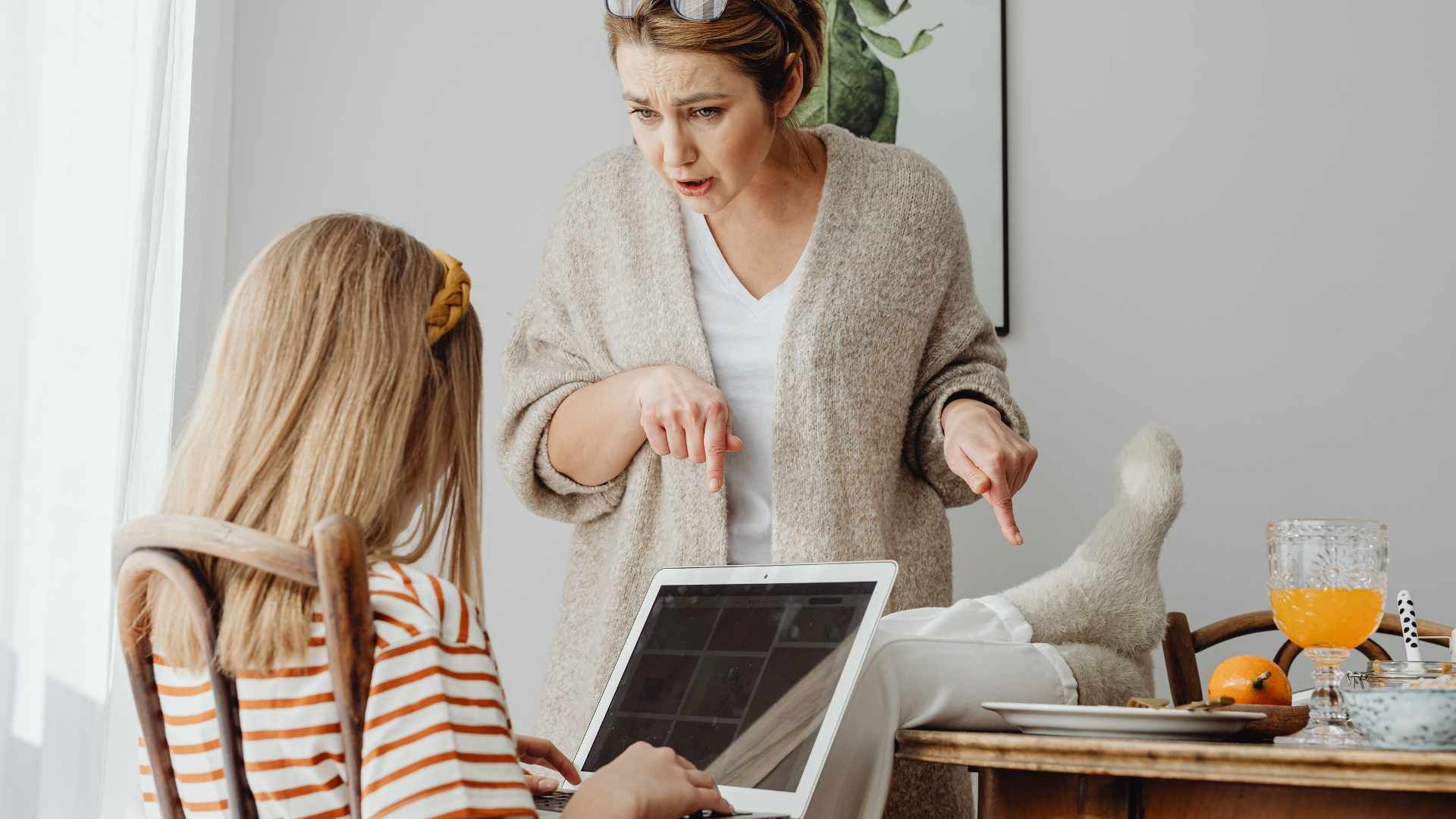 one woman asking the other woman whos on the computer to remove her feet on the table