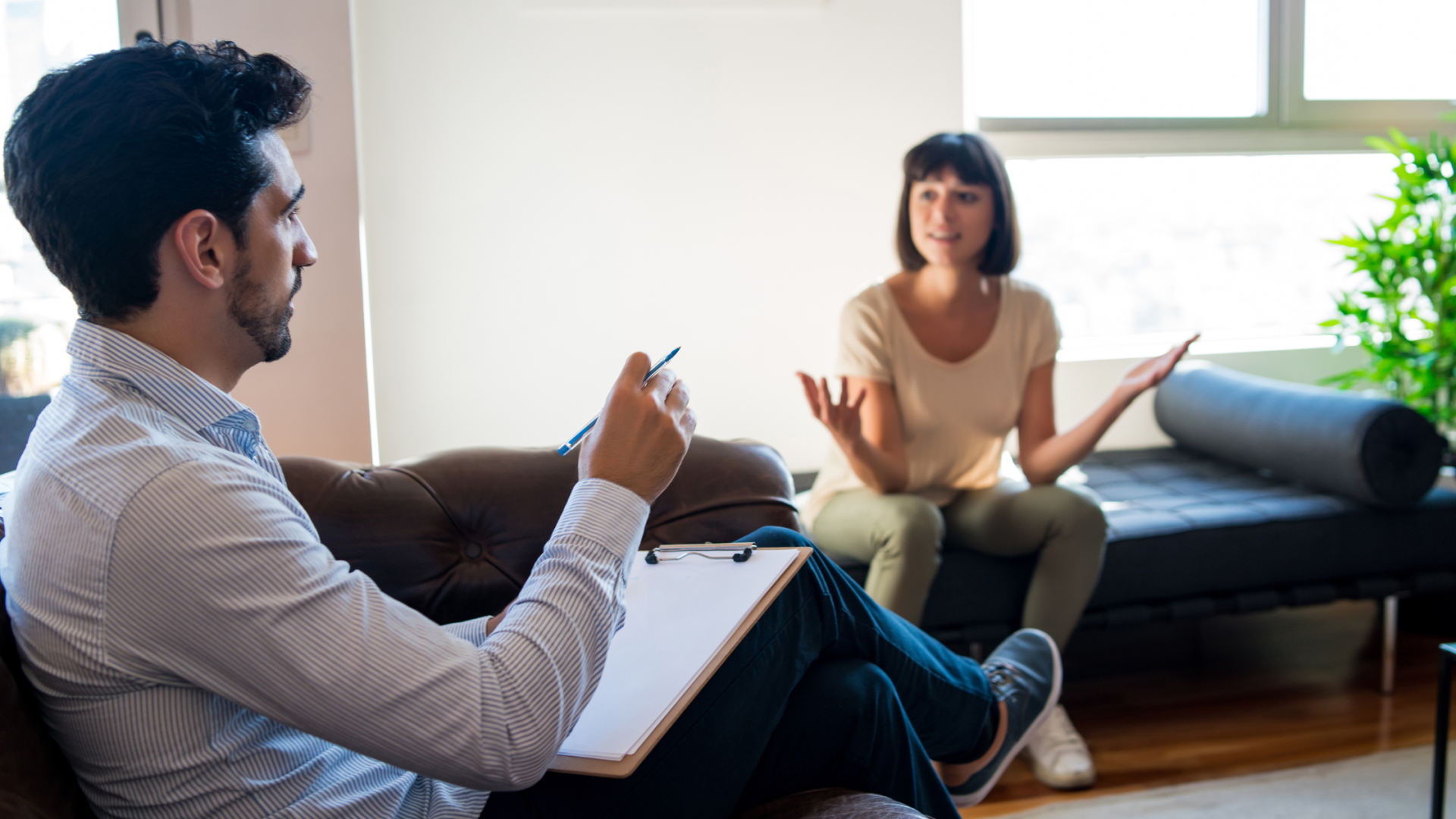 woman sitting on a couch speaking to her therapist across the room