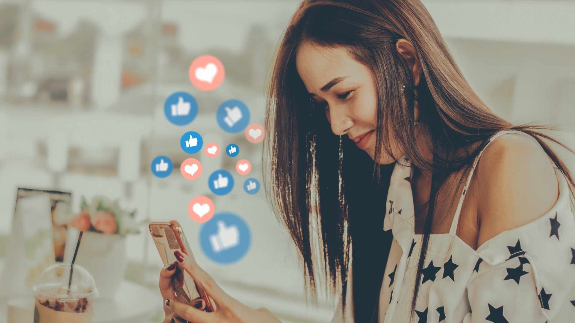 woman on her phone smiling as she receives hearts and likes on social media