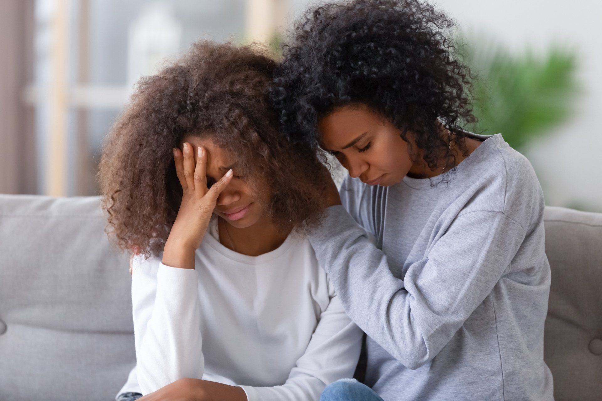 mother comforting her teenage daughter on the couch