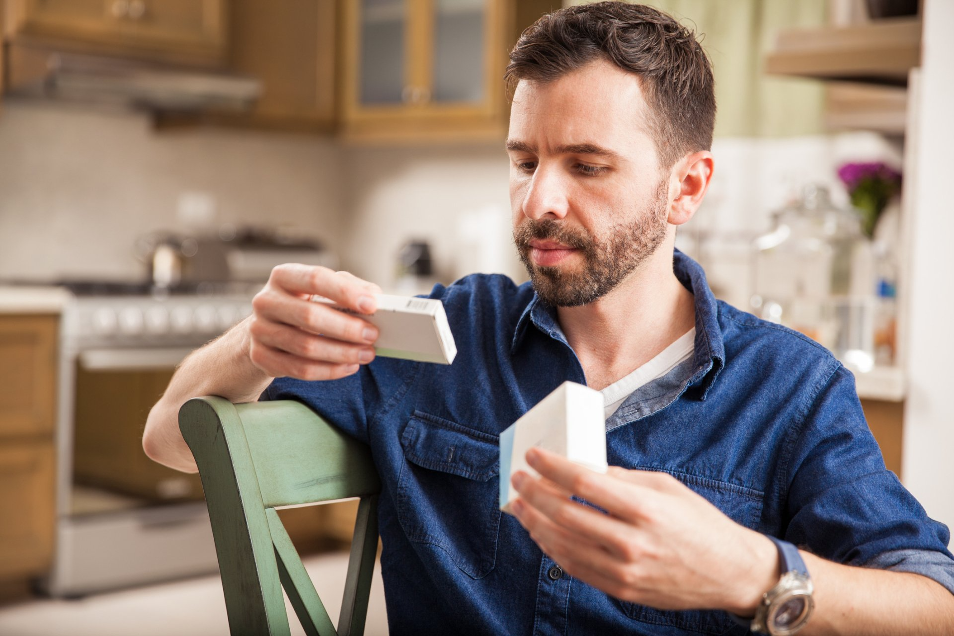 man reading from the boxes of medications he is holding