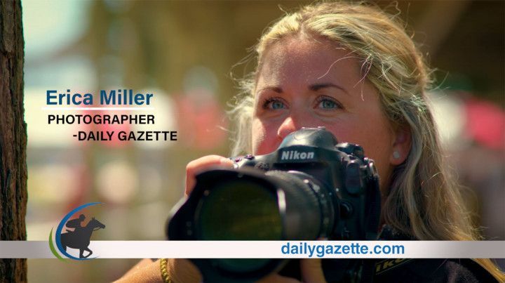 Erica Miller, photographer, holding a Nikon camera; Daily Gazette. Blond woman outdoors, taking a photo.