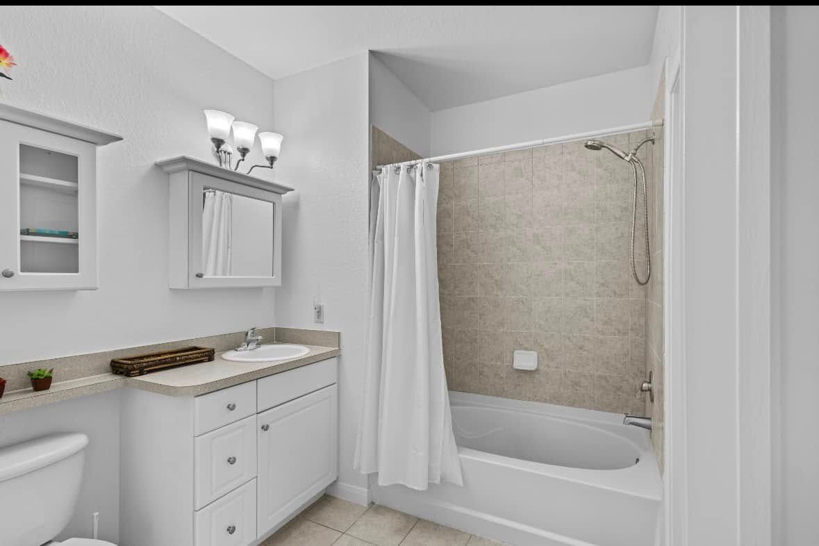 White bathroom with vanity, toilet, and bathtub/shower.
