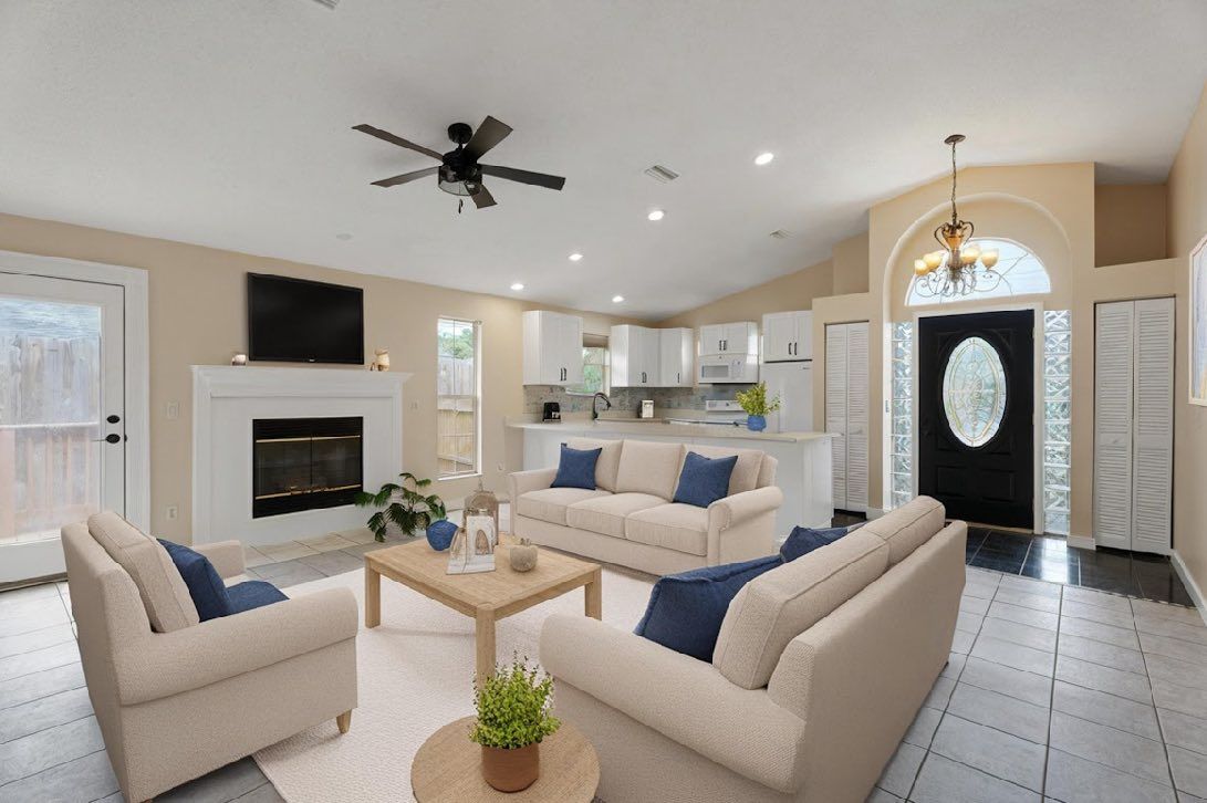 Living room with fireplace, sofas, and open kitchen; neutral colors, natural light.