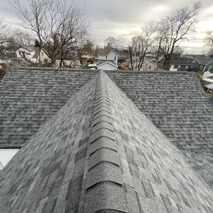 View from a roof apex, showing gray shingles and houses in the background.