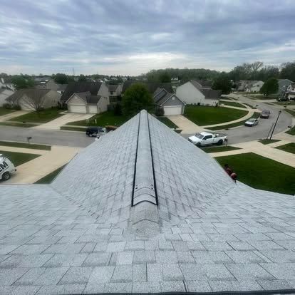 Rooftop with gray shingles, overlooking a suburban neighborhood on a cloudy day.