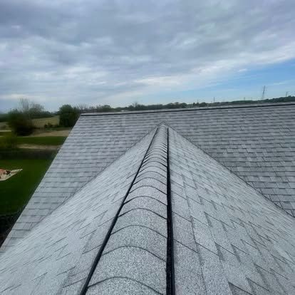 Gray shingle roof of a house under a cloudy sky.