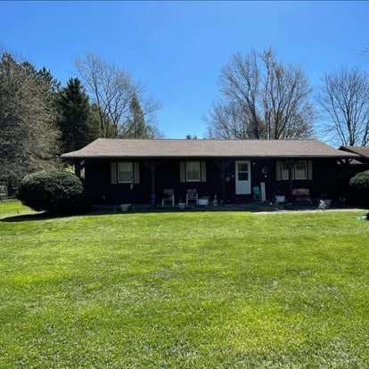 Black ranch home with green lawn on a sunny day.