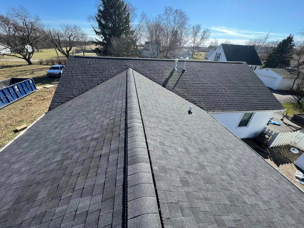 Newly shingled gray roof on a house, seen from above on a sunny day.