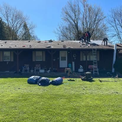 Roofers on a residential home installing a new roof under a bright blue sky.