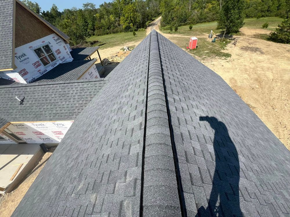View from a rooftop, showing gray shingles, a ridgeline, and a construction site in the background.